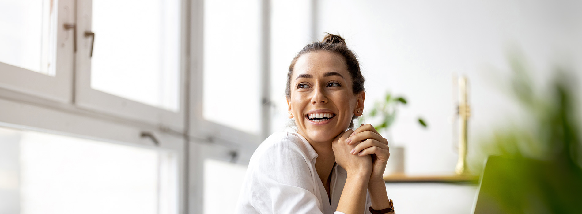The image is a photograph of a woman with light skin, smiling at the camera. She appears to be in her late twenties or early thirties and has long hair. Her eyes are looking directly at the camera, and she is holding up her index finger near her mouth as if she s making a point or emphasizing something. The background is plain and light-colored, which suggests that this could be a stock photo used for various purposes such as advertising, personal branding, or lifestyle content.