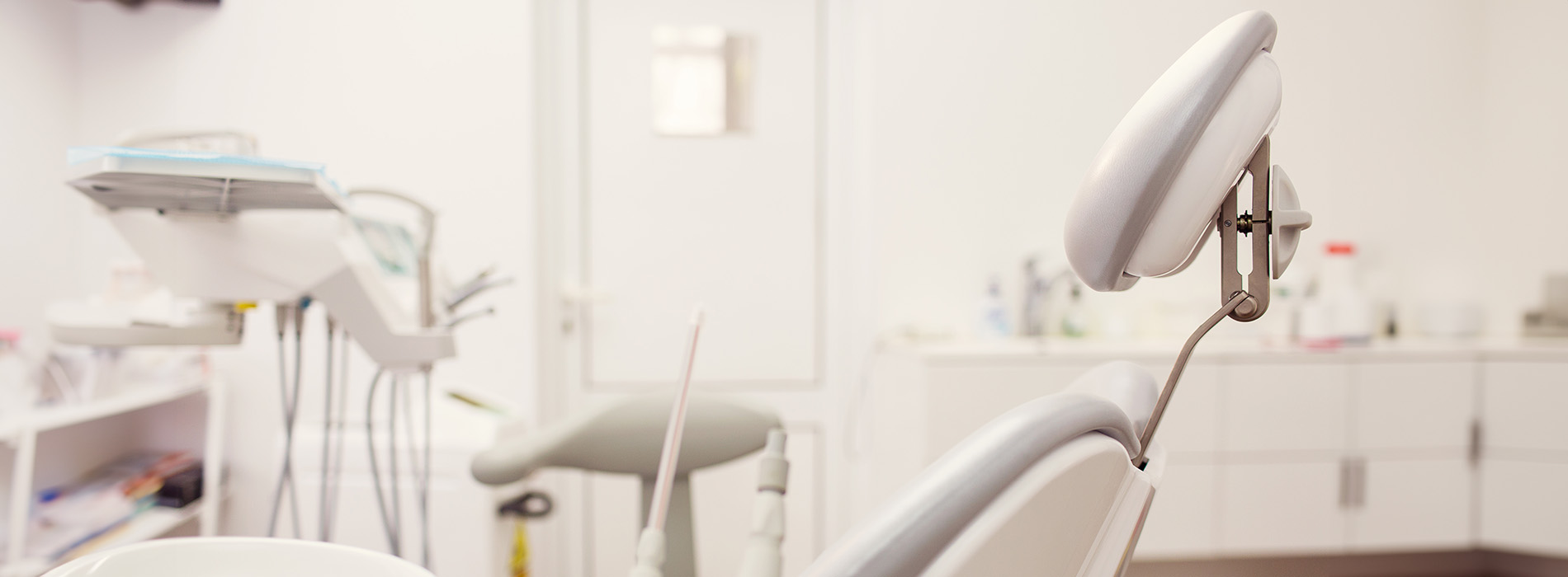 The image shows a modern dental clinic interior with various pieces of equipment, including a dental chair and an X-ray machine.