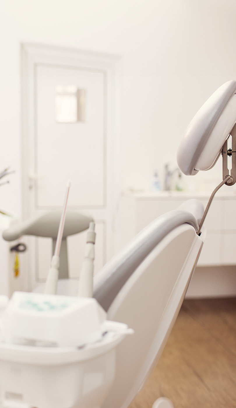 The image shows a modern dental or medical office interior with a dental chair, equipment, and a clean, professional environment.